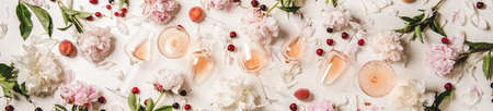 Rose wine variety layout. Flat-lay of rose wine in glasses with flowers and summer fruit over white background, top view, wide composition. Summer drink for party, wine shop or wine tasting conceptの写真素材
