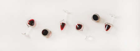 Red wine in glasses. Flat-lay of wine glasses with red wine in row over plain white background, top view. Wine tasting, winery, bar or Beaujolais Nouveau conceptの写真素材