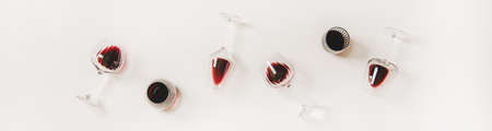 Red wine in glasses. Flat-lay of wine glasses with red wine in row over plain white background, top view, wide composition. Wine tasting, winery, bar or Beaujolais Nouveau conceptの写真素材