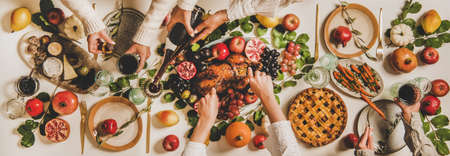 Autumn Thanksgiving, Friendsgiving, family party dinner. Flat-lay of peoples hands eating and drinking over table with roasted duck, vegetables, cheese board and apple pie, top viewの写真素材