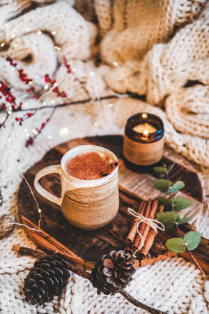 Turkish traditional wintertime hot drink Salep. Mug of sweet warming Salep drink with ground cinnamon on tray over knitted blanket. Turkish seasonal cuisine, Christmas and New Year moodの写真素材