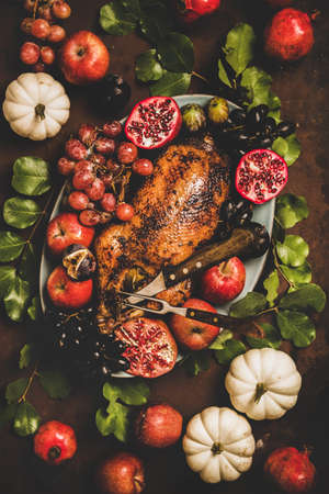 Autumn Thanksgiving, Friendsgiving, family party gathering celebration dinner. Flat-lay of Fall table with roasted duck in seasonal fruits decorated with pumpkins and leaves over rusty backgroundの写真素材