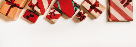 Flat-lay of festive craft gift boxes in wrapping paper decorated with colorful baubles, ribbons and bows over plain white background, top view, copy space. . Christmas boxing day conceptの写真素材
