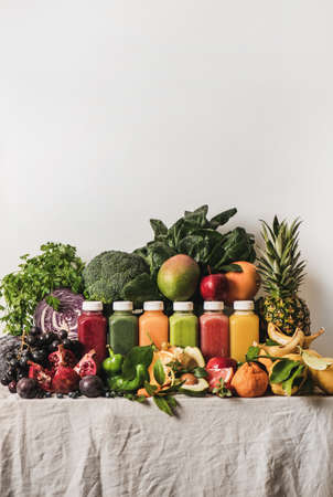 Variety of fresh colorful smoothies for detox weight loss diet. Juices in vacuum bottles with fruit, vegetables and greens ingredients on tablecloth, copy space. Vegan, vegetarian, clean eating foodの写真素材