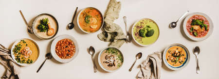 Flat-lay of vegetarian creamy homemade soup and spoons over white plain table background, top view. Autumn and Winter creamy vegan soups, fall and winter vegetarian food menu conceptの写真素材