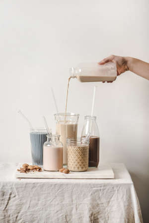 Almond dairy-free milk with blue matcha, berries, coffee, cinnamon, cocoa in bottles and glasses and...