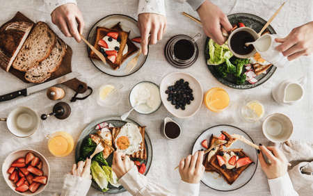 People having breakfast with coffee and snacks over white table