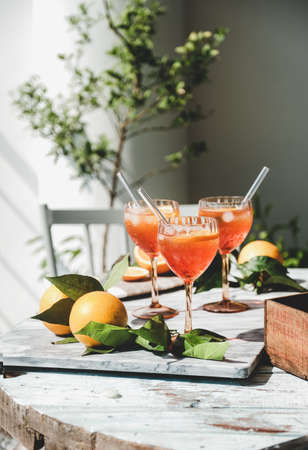 Aperol Spritz cocktail in glasses with oranges on tableの写真素材