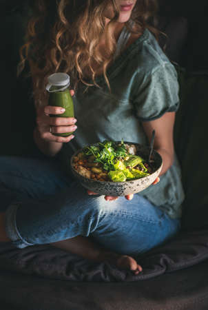 Woman sitting on chair and holding healthy superbowl and smoothieの写真素材