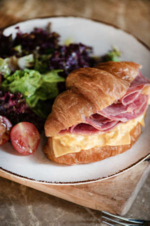 Ham, cheddar cheese and scrumbled egg stuffed French croissant, close-upの写真素材