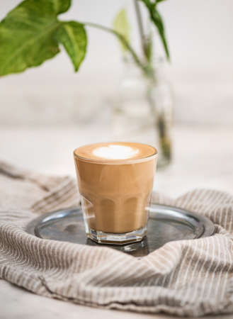 Glass of flat white coffee with heart shaped foam milkの写真素材
