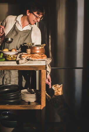Woman cooking Turkish traditional meat soup Haslama and touching catの写真素材