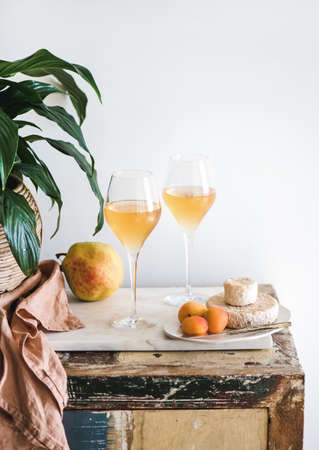 Orange or Amber wine in glasses, fruits and cheeseの写真素材