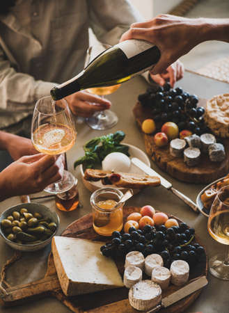 Human hand pouring white orange or rose wine from bottleの写真素材