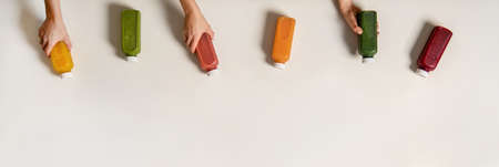 Flat-lay of human hands holding fresh juices in bottlesの写真素材