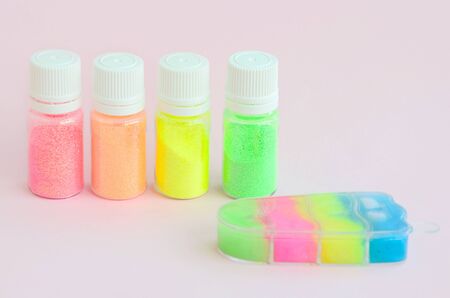 Colorful glitters lies on pastel pink background. Many round jars with multi-colored bright sparkles for nail polish. Sparkling sequinsの写真素材