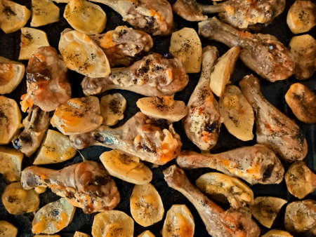 Baked chicken legs and potatoes lie in bakingの写真素材