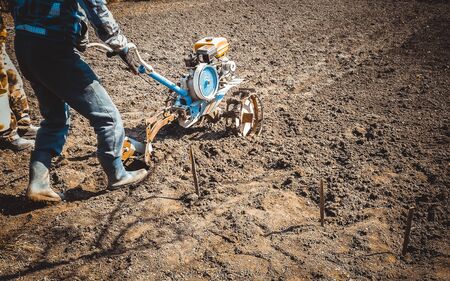 The man plows the land with a cultivator