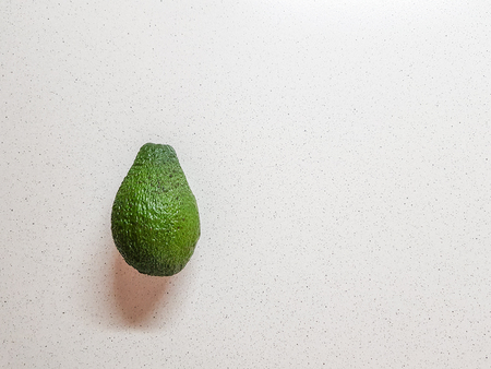 Ripe avocado in hand. White bakcground. Side view