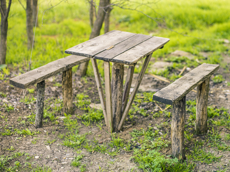 rural wooden table and two benches in the yard on the grassの写真素材