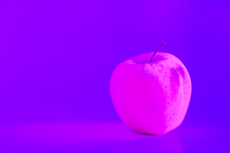 One apple on the table. Pink tone. Copy space