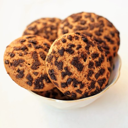 Oatmeal cookies, sprinkled with chocolate slices. Sweet dessert in a small saucer on a white table. White backgroundの写真素材