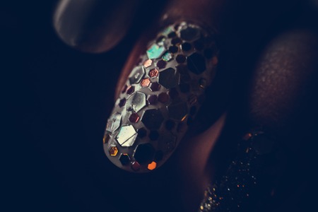Fingers with white lacquer and with pentagons of different sizes on the nails.の写真素材