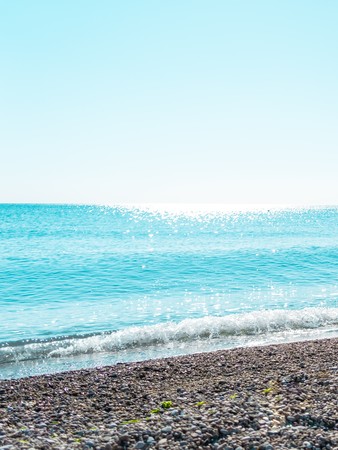 Pebble beach, black sea and blue sky on background.の写真素材