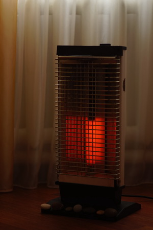 Vintage electric heater Ugolek with a burning lamp closeup. Selective focus.