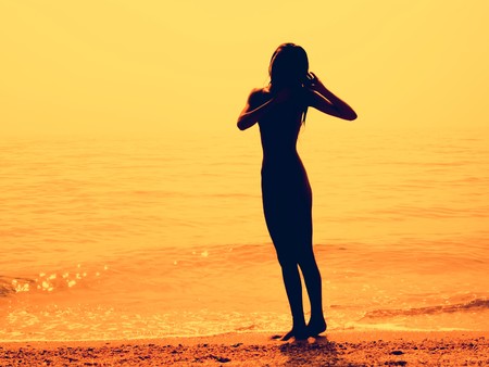 Silhouette of a skinny young girl walking along the beachの写真素材