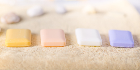 Four solid pieces of soap lie on a pale brown towel. Sea shells in the back. Side view with...