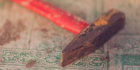 Old red hammer lies on a table with a dirty tablecloth.の写真素材