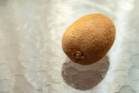 whole kiwi fruit on a glass table.の写真素材