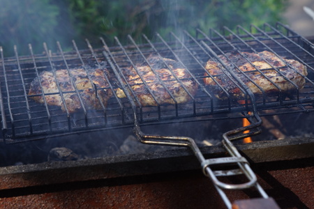 Large pieces of pork meat are prepared in the closed grill