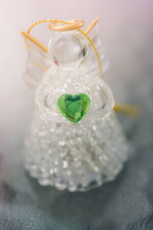 glass angel with green heart and sunlightの写真素材