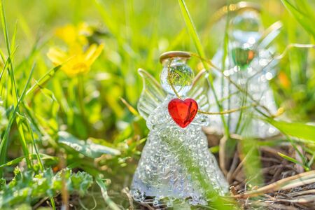 Two angels with red and green hearts in hands stands among the bright grass in the spring field. Call to love and care about nature. The concept of environmental protection.の写真素材
