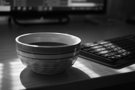 freelancer workspace, tea cup, keyboard and monitor, work environment, selective focus, bw photoの写真素材