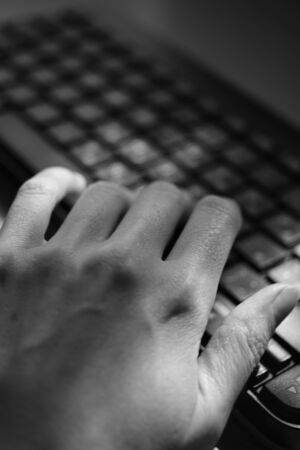 female hand is typing on the keyboard, selective focus on the finger, black and white photoの写真素材