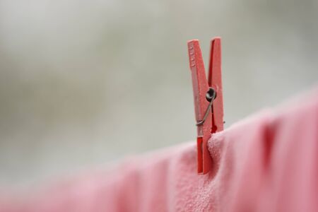 Red clothespin holds clothes on a rope, macro image.の写真素材