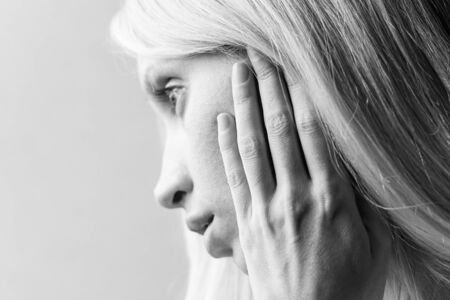 Soft portrait of a young girl with hand on her cheek, side view in profile, black and white photoの写真素材