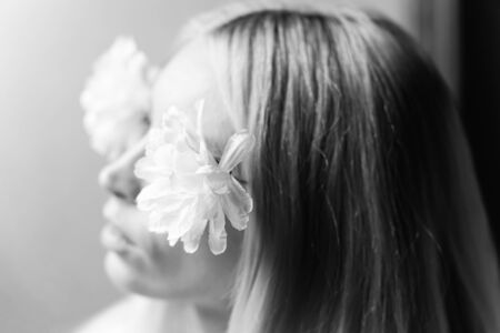 Blurred portrait of a young girl with flowers in her hair, female dreams and pleasure. Selective soft focus. Black and white.の写真素材