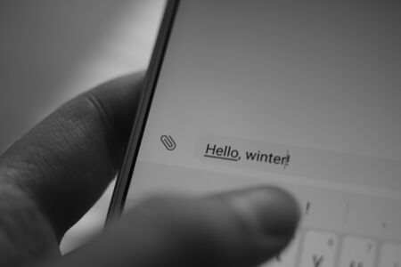 hand typing on a white smartphone a message Hello, winterの写真素材