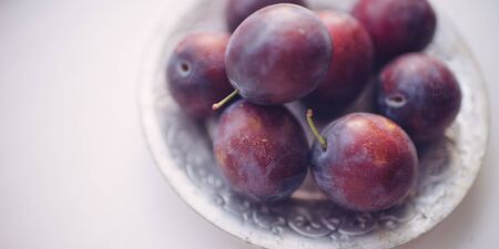 Ripe purple plums in a silver plate closeupの写真素材