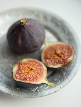 Two ripe figs. One whole fig and the second cut in half on a white table. Selective focusの写真素材