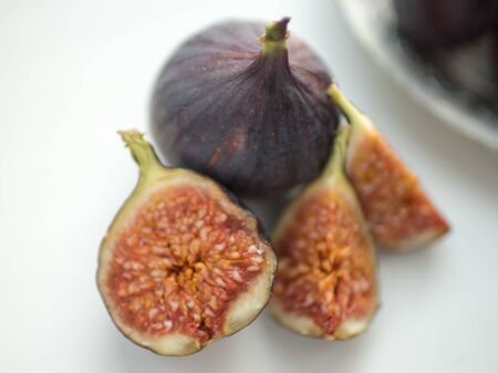 One whole fig and the other sliced lie on a white tableの写真素材