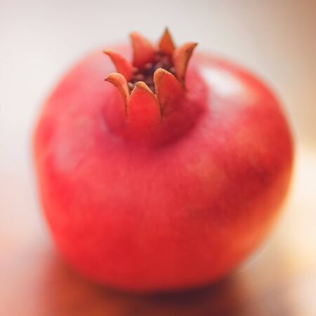 Whole ripe pomegranate close up on the sunny tableの写真素材