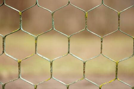 old rusty hexagonal mesh fence with blurred bokeh