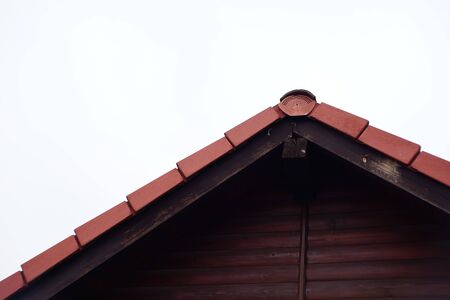 Part of the pediment of a wooden house with a red roof metal tile