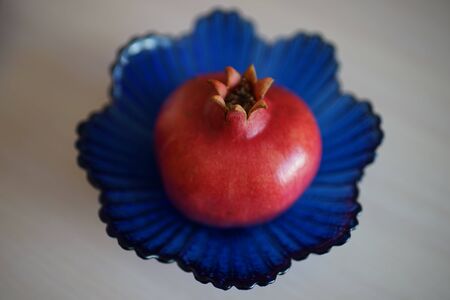 Whole ripe pomegranate on the blue crystal vaseの写真素材