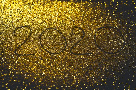 Flickering greeting card with a gold inscription 2020 on a golden backgroundの写真素材